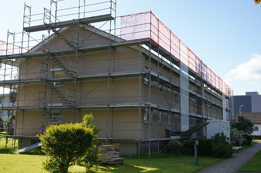Front and side view on residential apartment house in Switzerland with scaffolding and protective net.