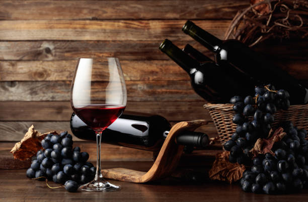 istock Red wine and blue grapes on an old wooden table. 1421085373