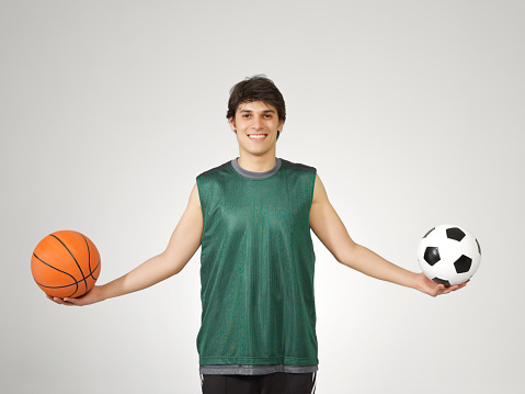Young sportsman holding a soccer ball and a basketball