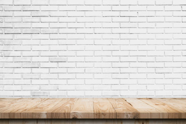 istock Empty wooden table top and white brick wall and rough crack background texture 1421086616