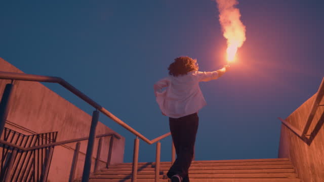 Teenager running up stairs with burning signal flare in raised hand