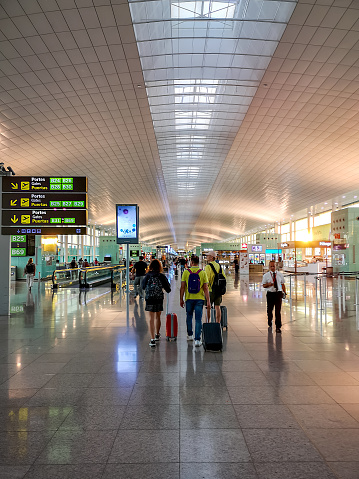 Barcelona, Spain - September 8, 2019: Tourists walking at the public area at the Terminal T1 of El Prat-Barcelona airport. This airport was inaugurated in 1963. Airport is one of the biggest in Europe and one of the busiest in the world. People are walking.