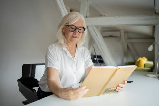 istock Happy woman reading book at home 1421093936