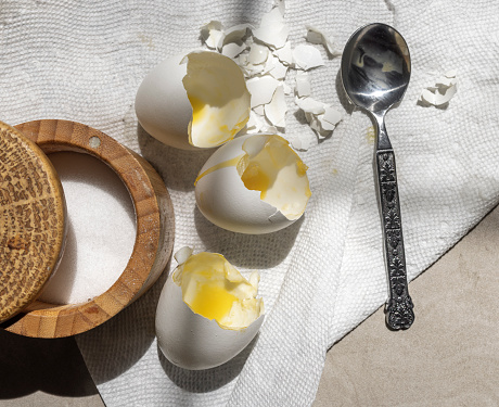 Broken eggs and opened saltcellar left on the kitchen table after cooking an omelette.