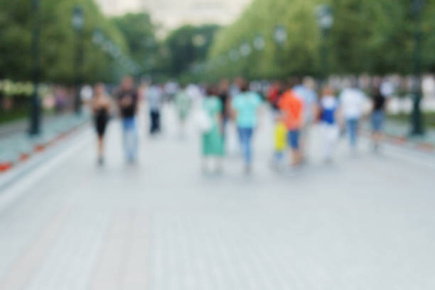 Abstract blurred defocused background with people walking on the street. Unrecognizable faces.