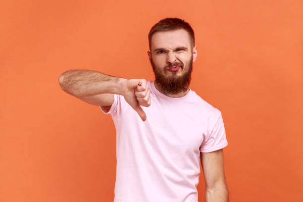 istock Man criticizing bad quality with thumbs down displeased grimace, showing dislike gesture. 1421095889