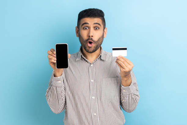 istock Man holding and showing empty display smartphone and credit card, shocked with easy mobile banking. 1421096043