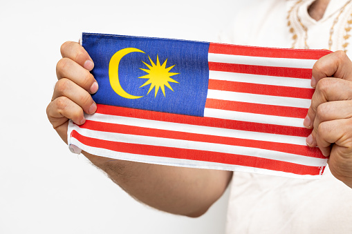 Asian woman in business attire running in Kuala Lumpur city with MAlaysian flag