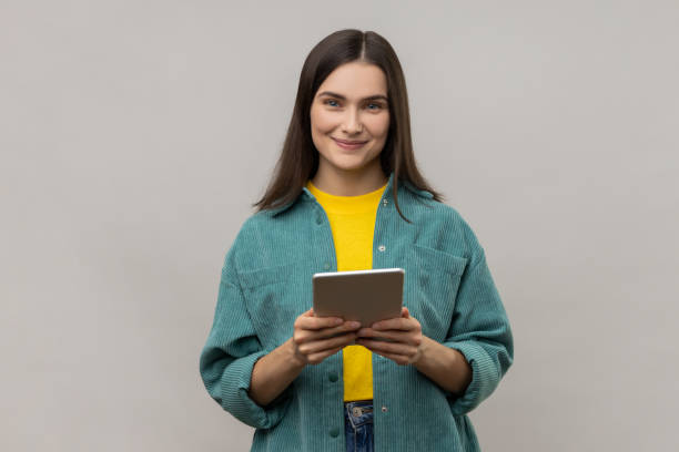 woman using tablet for checking social networks, looking at camera with positive expression. - isolated holding letter people imagens e fotografias de stock