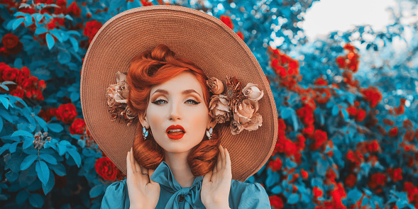 Awesome redhead model expresses emotions. Valentines Day background. Fabulous retro girl with red lips in mint dress on awesome summer background. Woman portrait. Roses bush.