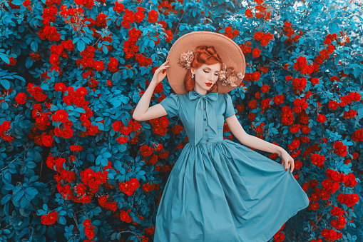 Awesome redhead model expresses emotions. Valentines Day background. Fabulous retro girl with red lips in mint dress on awesome summer background. Woman portrait. Roses bush.