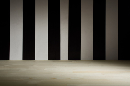 Empty wooden surface and striped black and white wall background in the dark