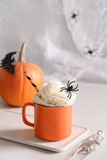 Halloween pumpkin latte coffee with whipped cream decorated spiders Halloween pumpkin latte coffee with whipped cream decorated spiders on white background. Vertical format. Horror funny food. gross coffee stock pictures, royalty-free photos & images