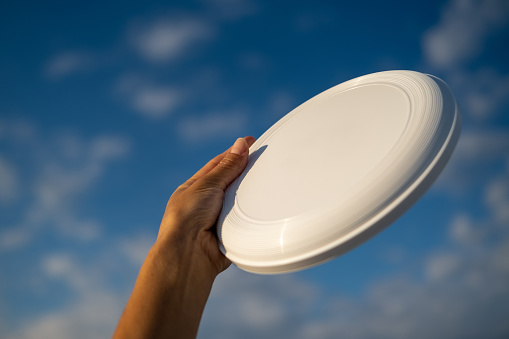 Close up on white plastic frisbee against beautiful blue sky.