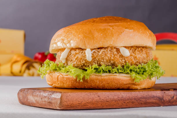 istock Crispy juicy Chicken Burger Meal isolated on wooden board side view on grey background fastfood 1421102768