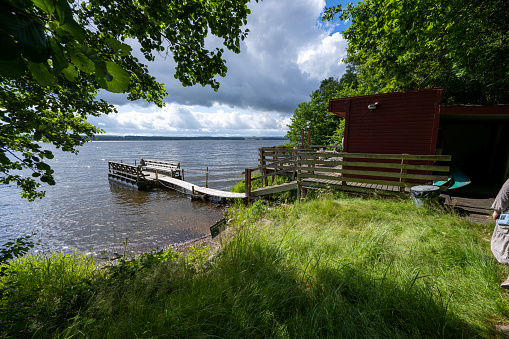 Two adirondack chairs sit on a small deck by the ocean with a Canadian flag.