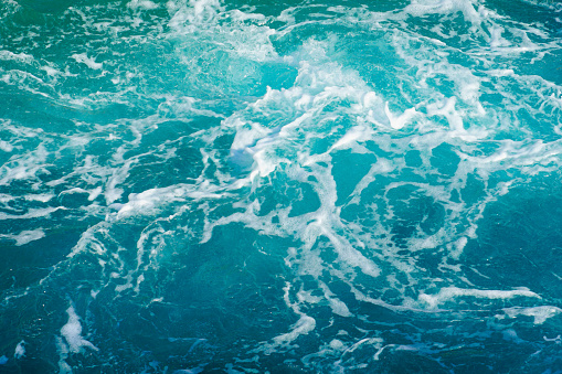 Big turquoise abstract of sea surface with turbulent white foam on the top
