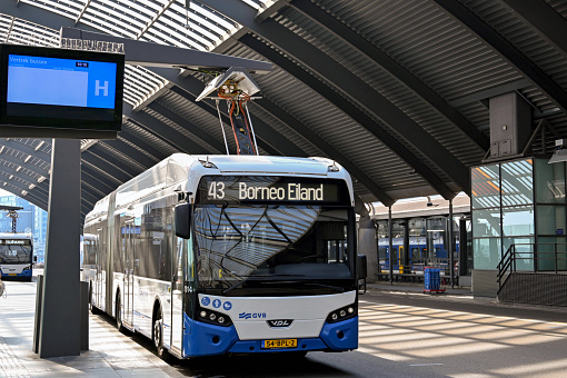 Amsterdam, Netherlands - August 2022: Public service bus connected to a rapid electricity chraging station in the bus station at Amsterdam's Centraale railway station