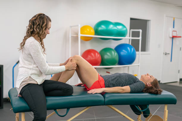 istock Physical therapist stretching out her female patient on a massage table 1421112190