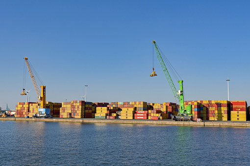Antwerp, Belgium - August 2022: Cranes and shipping containers stored on the side of the city's commercial port