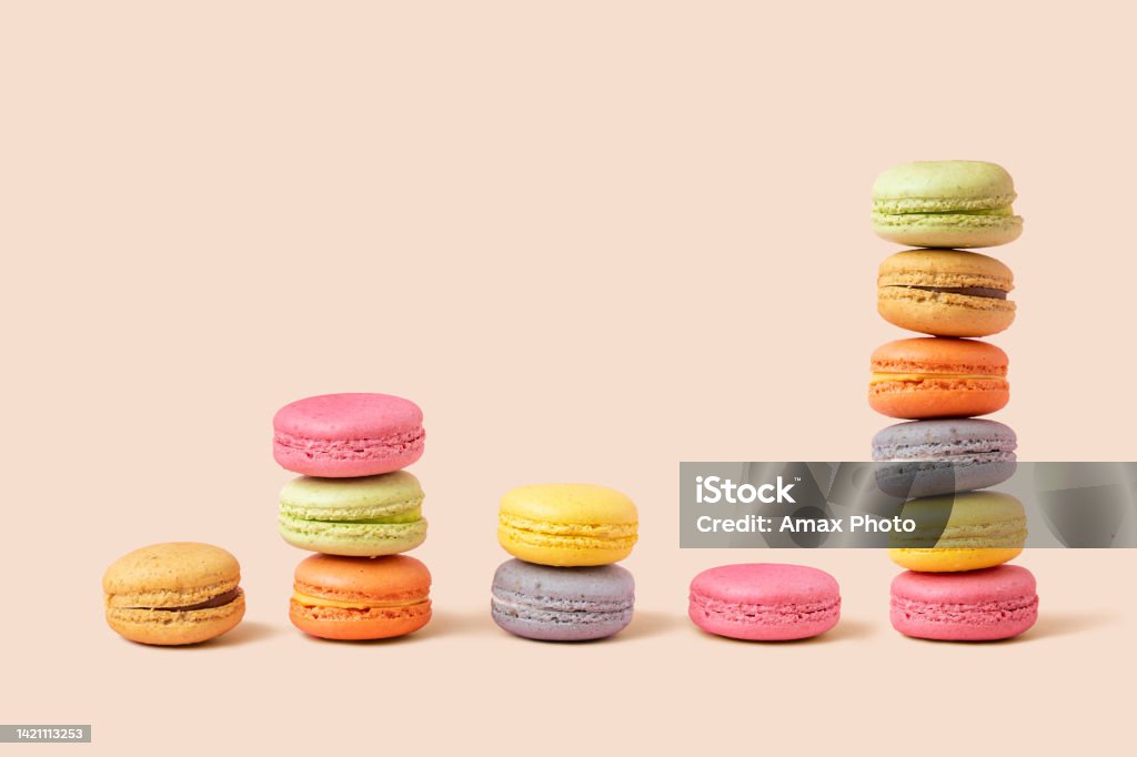 Stack and diagram of macaroons as coins, forming a financial graph on beige background. Metaphors and concept Macaroon Stock Photo