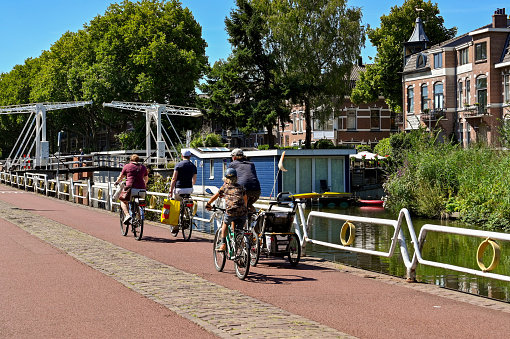 Utrecht, Netherlands - August 2022: Family cycling on a road alongside a canal near the city centre