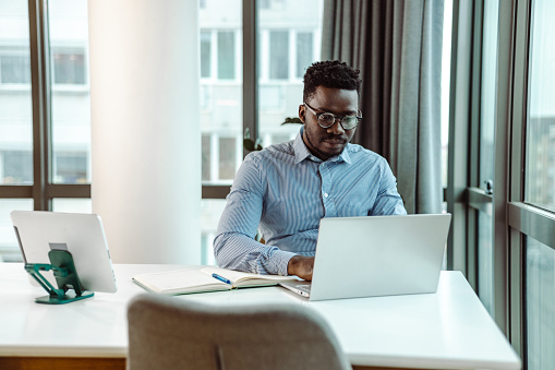 Portrait of African-American businessman using a laptop at the office. He is concentrating on his work