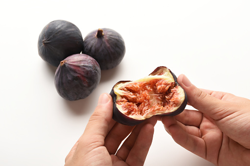Eating figs, hand opened figs for eating and group of whole figs on the white background
