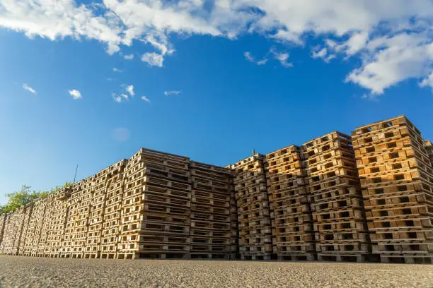 Stacks of wooden pallets in a warehouse yard of factory. Pallets for transportation of goods in a transport company.