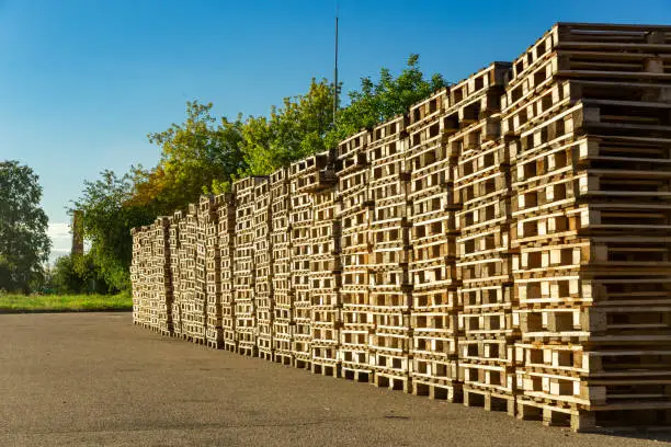 Stacks of wooden pallets in a warehouse yard of factory. Pallets for transportation of goods in a transport company.