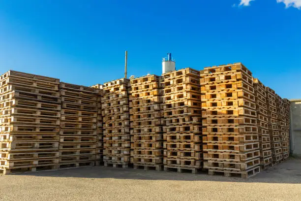 Stacks of wooden pallets in a warehouse yard of factory. Pallets for transportation of goods in a transport company.