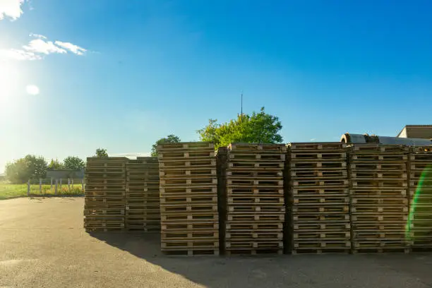 Stacks of wooden pallets in a warehouse yard of factory. Pallets for transportation of goods in a transport company.