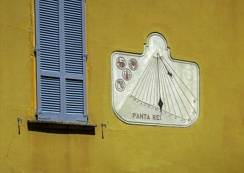 a sun dial on the side of a building in downtown Bellagio, Italy, on the shore of Lake Como.  Panta rei is the  ancient Greek saying, \