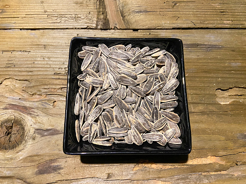 Sunflower seeds in the porcelain bowl on the wood table background