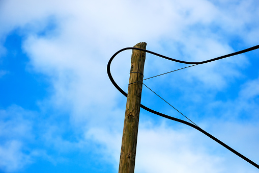 Old wooden electricity pylon with cables and sky background