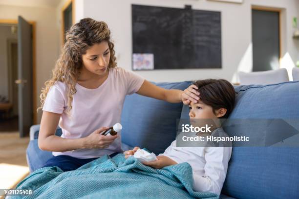 Mother At Home Checking If Her Sick Son Has Fever Stock Photo - Download Image Now - Fever, Child, Forehead