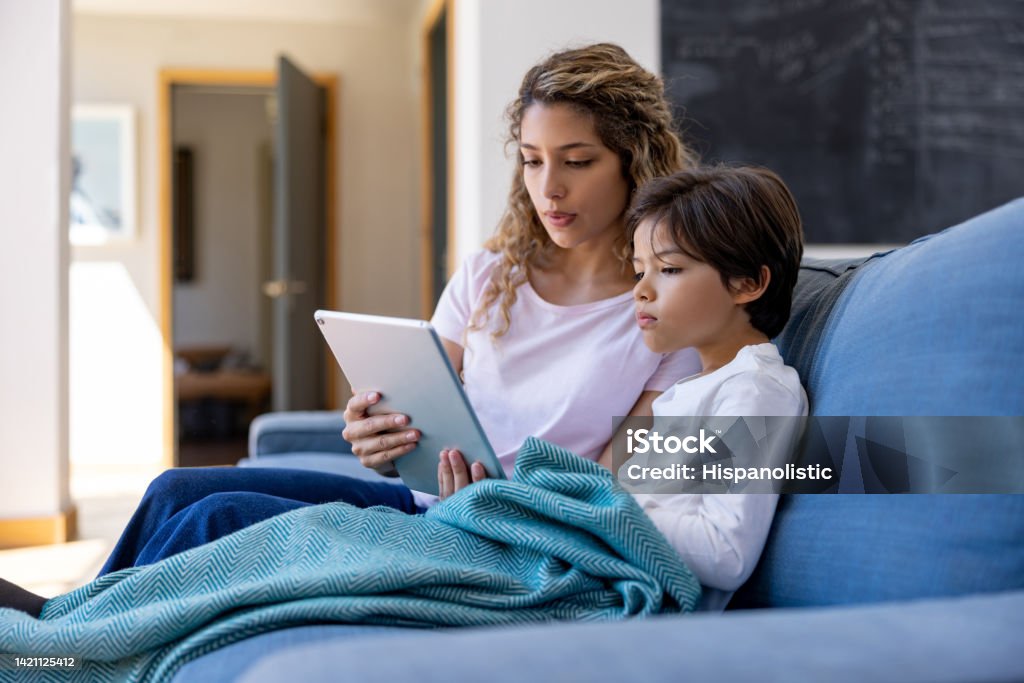 Mother and her sick son talking to the doctor on a video call from home Latin American mother and her sick son talking to the doctor on a video call - telemedicine concepts Telemedicine Stock Photo