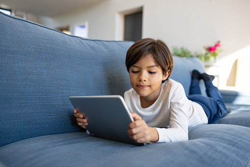 Latin American boy using his tablet computer at home - screen time concepts