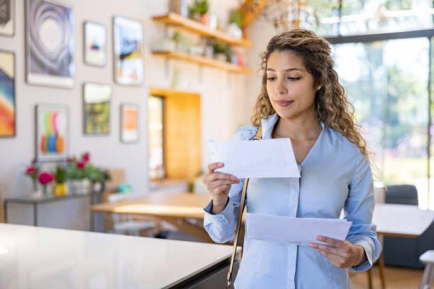 istock Woman arriving home and reading a letter in the mail 1421125607