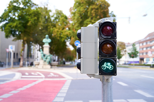 A bicycle traffic light that is green. Bike lanes are blurred in the background. Sustainable and ecological road traffic. Organized transport with bicycle zones for cyclists.