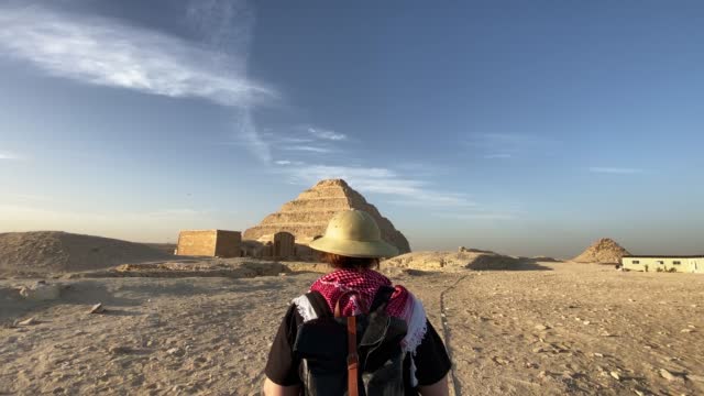back view of woman walking towards the step pyramid at Saqqara ,