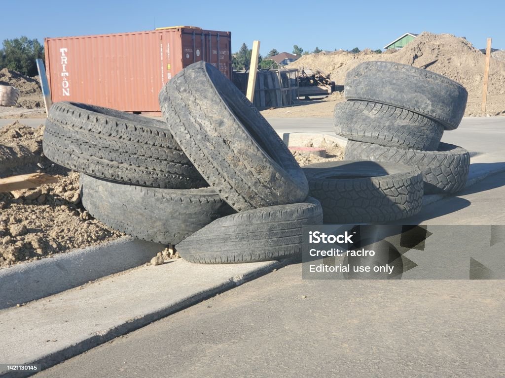 Pile of used tires at a large construction site. Superior, Colorado, USA-September 4, 2022:Ongoing construction site with several used tires stacked on a curb and unfinished road. Incomplete Stock Photo