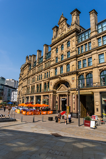 Manchester United Kingdom Historic Corn Exchange building in central Manchester. People can be seen on the plaza in front of it in morning light.