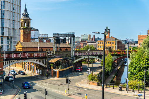 Manchester United Kingdom Deansgate railway station with a view over a canal. Cars are visible on the streets.