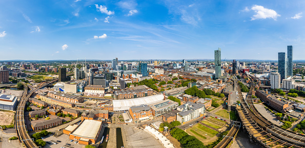 Manchester United Kingdom aerial shot of modern buildings with lots of counstruction in the central area of the city with historic canals and railways in the foreground