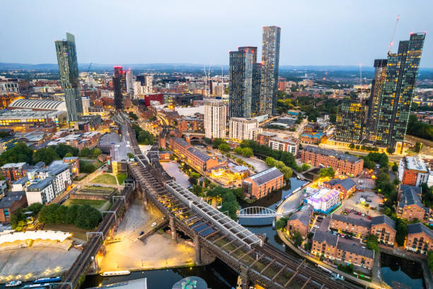 Manchester United Kingdom aerial shot of modern buildings with lots of counstruction in the central area of the city with historic canals and railways in the foreground by night stock photo