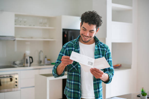 homem feliz lendo boas notícias em uma carta no correio - bill looking cheerful latin american and hispanic ethnicity - fotografias e filmes do acervo