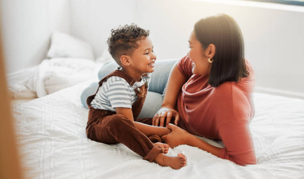 cura dei bambini, amore e madre premurosa che gioca con il figlio piccolo in camera da letto, insegnandogli a parlare in una stanza da letto a casa. genitore single o mamma che mostra amore, affetto e cura per il bambino, legando insieme - bambino piccolo foto e immagini stock