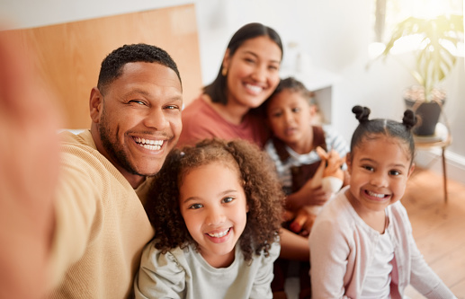 Happy family taking selfie, having fun, relaxing and bonding in living room at home. Smiling, carefree parents enjoying time with children indoors, being affectionate and together on the weekend