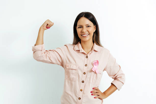 Young Brazilian woman with breast cancer ribbon over white background Young Brazilian woman with breast cancer ribbon over white background breast photos stock pictures, royalty-free photos & images